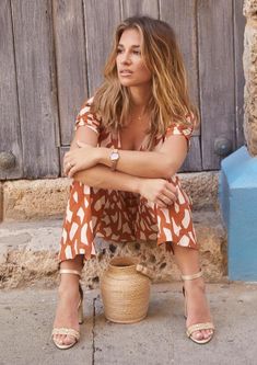 a woman sitting on the ground with her arms crossed and legs crossed, leaning against a basket