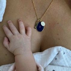 a close up of a person holding a baby's hand with a necklace on it