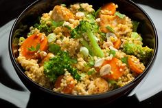 a bowl filled with rice, broccoli and carrots on top of a table