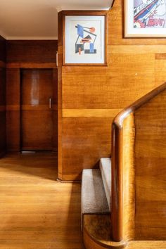 a wooden staircase leading up to a painting on the wall above it and below it is a wood paneled stair case