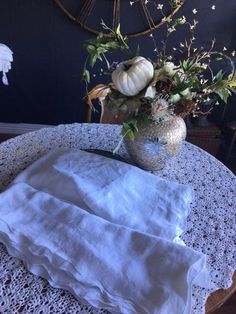 a vase with flowers sitting on top of a table next to a lace doily