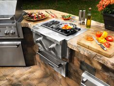 an outdoor kitchen with stainless steel appliances and grilling materials on the counter top, outside