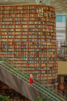 a woman is walking down an escalator in front of a large book store