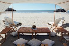 chairs and tables on the beach under umbrellas