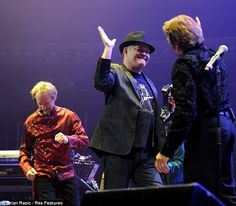 three men on stage with one holding his hand up in the air