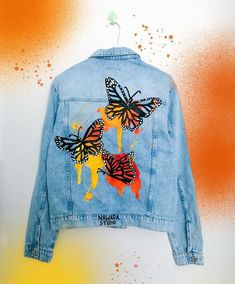 a blue jean jacket with butterflies painted on it