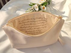 a white purse sitting on top of a table next to a bouquet of daisies