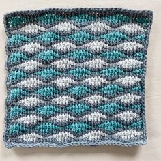 a crocheted dishcloth with blue and white designs on it sitting on a table