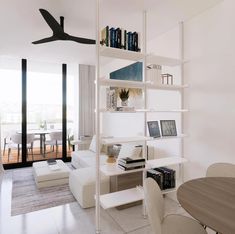 a living room filled with furniture and a white book shelf next to a dining table