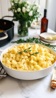 a white bowl filled with macaroni and cheese on top of a marble table