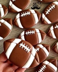 decorated cookies in the shape of footballs are being held by someone's hand