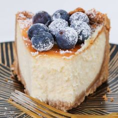 a piece of cheesecake topped with blueberries and powdered sugar