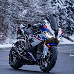 the motorcycle is parked on the side of the road in front of snow covered trees