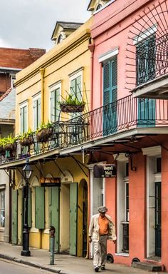 a man walking down the street in front of some colorful buildings with balconies