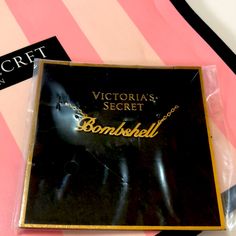 the victoria's secret bombshell necklace is in its packaging on a pink and black striped background