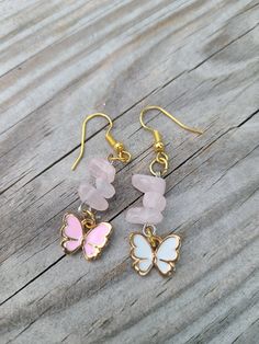 A pair of earrings with butterfly enameled charms and rose quartz chip beads. One butterfly is pink and the other white. Pink Butterfly Charm Earrings, Pink Butterfly Charm Drop Earrings, Pink Butterfly Charm Earrings As Gift, Pink Butterfly Charm Earrings For Gift, Handmade Pink Butterfly Earrings, Pink Drop Earrings With Butterfly Charm, Pink Rose Quartz Earrings Gift, Pink Rose Quartz Earrings For Gifts, Pink Butterfly Charm Dangle Jewelry