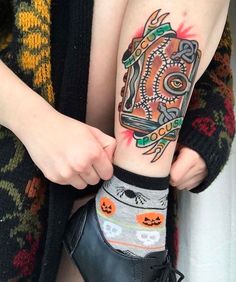 a person with a tattoo on their arm holding up a pair of black booties