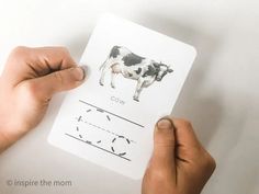 two hands holding up a piece of paper with an image of a cow