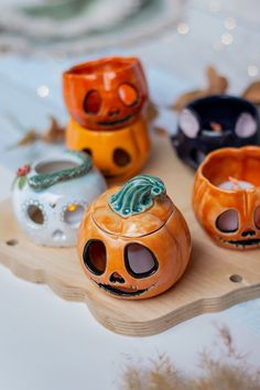 three ceramic pumpkins sitting on top of a wooden tray with faces painted on them