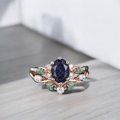 a blue and white diamond ring sitting on top of a wooden table next to a wall