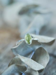 The rose cut peridot (August birthstone) shines alongside a tiny round green sapphire (September birthstone), both held securely in a bezel setting. Pair your peridot ring with peridot earrings to channel a free spirited and joyful vibe. Let this ring be the statement piece that adds a touch of whimsy and elegance to your style. Each piece of our jewelry is handcrafted with love. Green Peridot Birthstone Ring, Dainty Style, Dainty Green Peridot Rings, Green Sapphire Ring In Sterling Silver, Green Sapphire Sterling Silver Ring For May Birthstone, Lime Green Peridot Birthstone Ring, Green Sapphire Ring For May Birthstone In Sterling Silver, Green Sapphire Ring Sterling Silver, May Birthstone, Green Solitaire Sapphire Ring In Sterling Silver, Peridot Bezel Setting Promise Ring