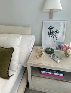 a white bed sitting next to a night stand with flowers on it and a lamp