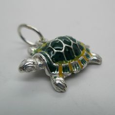 a green and yellow turtle charm sitting on top of a white table