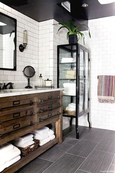 a bathroom with black and white tile, wooden cabinet, mirror, sink and towel rack