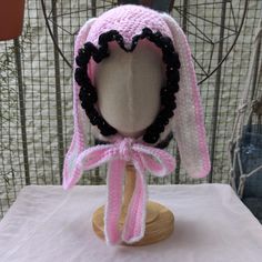 a pink and white hat on top of a wooden headdress with black beads