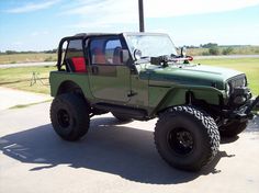 a green jeep parked on the side of a road