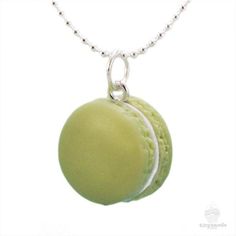 two green macaroons are hanging from a silver ball chain on a white background