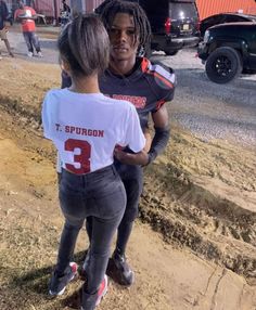 two girls in football uniforms standing on the side of a road