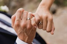 a man and woman holding hands with wedding rings on their fingers in front of them