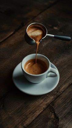 coffee being poured into a cup on a saucer