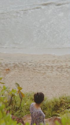 a woman standing on top of a sandy beach next to the ocean