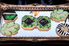 decorated cookies in the shape of flowers and leaves are displayed in an ornate gold frame