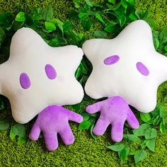 two purple and white hand puppets laying on top of green grass with leaves around them