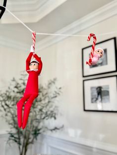 an elf hanging from a string with candy canes on it's head and two monkeys in the background