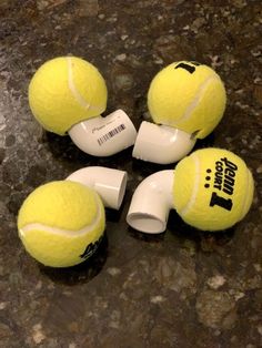 four tennis balls are sitting on the floor next to each other with ear buds attached