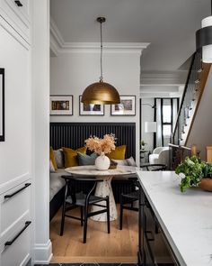 a dining room table with chairs and a vase on it in front of a staircase