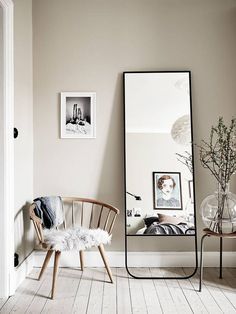 a room with a chair, mirror and pictures on the wall next to each other