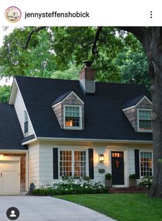 a white house with black shingles and two garage doors on the front door is shown