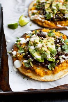 two flatbreads with black beans, avocado and sour cream on top