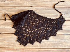 a black crocheted shawl on a wooden surface