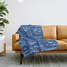 a couch with a blanket on top of it next to a potted plant in a living room