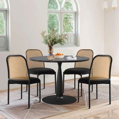 a dining table with four chairs and a potted plant in the corner on top