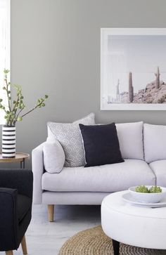 a white couch sitting next to a table with a bowl of fruit on top of it