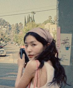 a woman walking down the street while holding a cell phone to her ear and wearing a headband