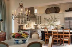 a dining room table and chairs in front of a kitchen with a chandelier