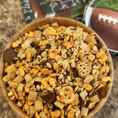 a wooden bowl filled with cheetos next to a football